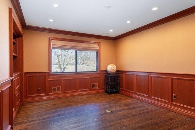 empty room with a wainscoted wall, recessed lighting, ornamental molding, and dark wood-style flooring