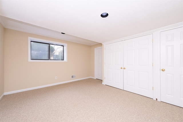 unfurnished bedroom featuring light colored carpet, visible vents, a closet, and baseboards