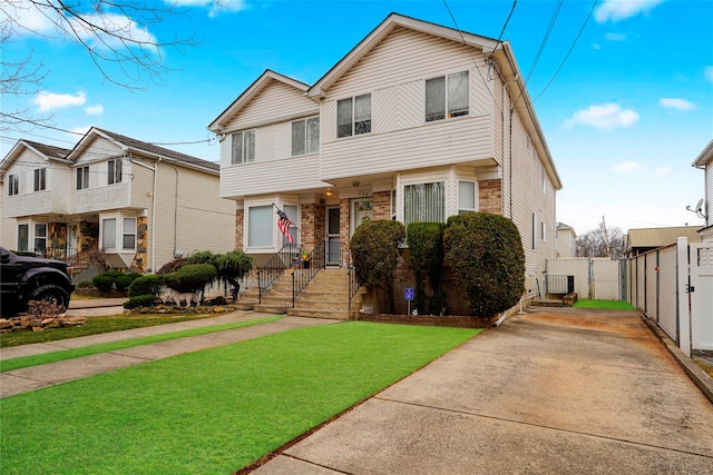 view of front of home with brick siding, a front yard, and fence