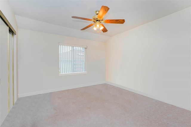 spare room featuring baseboards, carpet, a ceiling fan, and vaulted ceiling