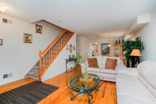 living area featuring visible vents, wood finished floors, and stairs