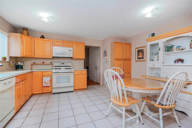 kitchen featuring white appliances, light brown cabinetry, and a sink