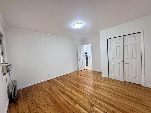 94-17 42nd Ave, Elmhurst, NY 11373 - unfurnished bedroom with light wood-style floors, a closet, crown molding, and baseboards