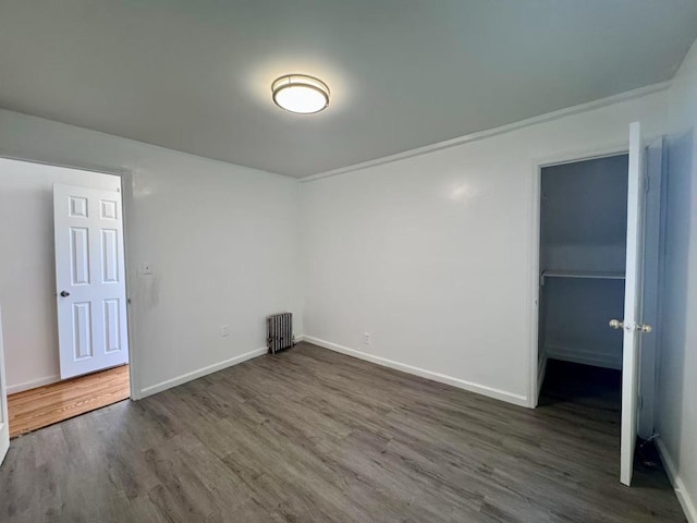 94-17 42nd Ave, Elmhurst, NY 11373 - unfurnished bedroom featuring a closet, a walk in closet, radiator heating unit, baseboards, and wood finished floors