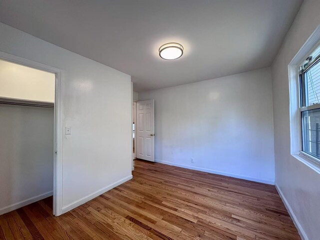 94-17 42nd Ave, Elmhurst, NY 11373 - unfurnished bedroom with wood finished floors, a closet, and baseboards