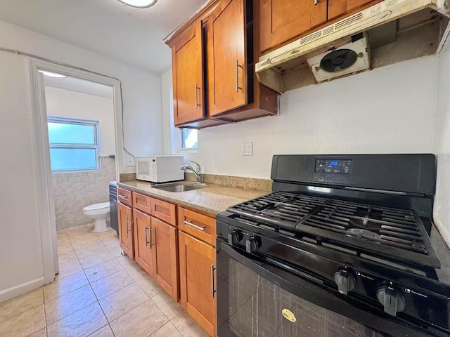 94-17 42nd Ave, Elmhurst, NY 11373 - kitchen with a sink, under cabinet range hood, brown cabinetry, white microwave, and black gas range oven