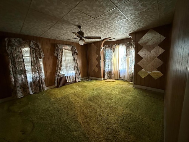 spare room featuring ceiling fan, carpet, and wood walls