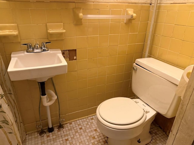 bathroom featuring tile patterned floors, toilet, and tile walls