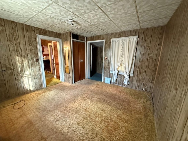 unfurnished bedroom featuring wood walls and carpet flooring