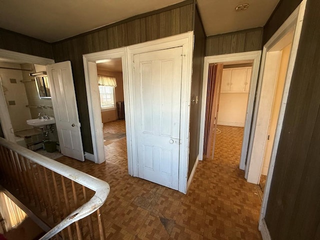 corridor featuring wood walls and a sink