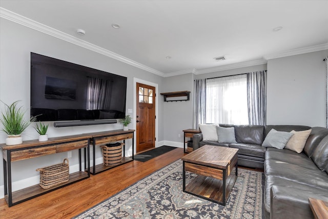 living room featuring visible vents, baseboards, wood finished floors, and crown molding