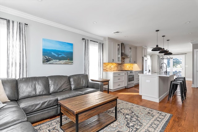 living room with visible vents, wood finished floors, and crown molding