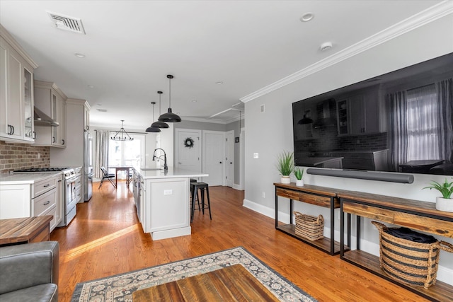 kitchen featuring visible vents, ornamental molding, tasteful backsplash, gas range oven, and light countertops