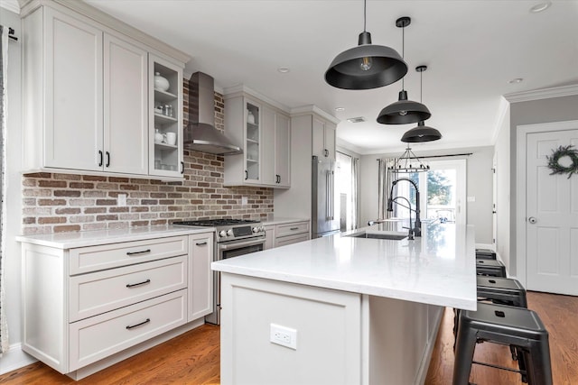 kitchen featuring crown molding, stainless steel appliances, wall chimney exhaust hood, and a sink