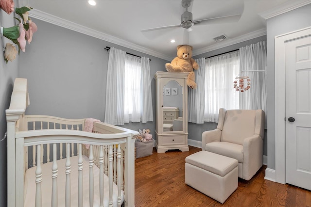 bedroom featuring a crib, multiple windows, wood finished floors, and ornamental molding