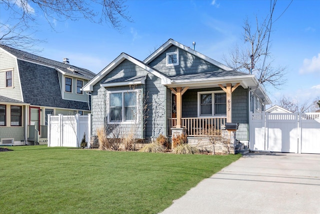 view of front facade with a porch, a shingled roof, a front yard, and fence