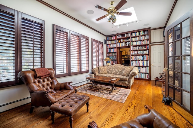 living area with baseboard heating, crown molding, a ceiling fan, and wood finished floors