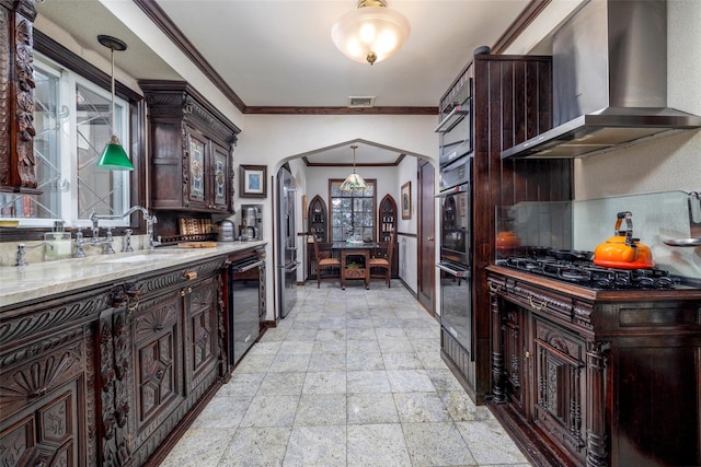 kitchen featuring visible vents, a sink, tasteful backsplash, arched walkways, and wall chimney exhaust hood