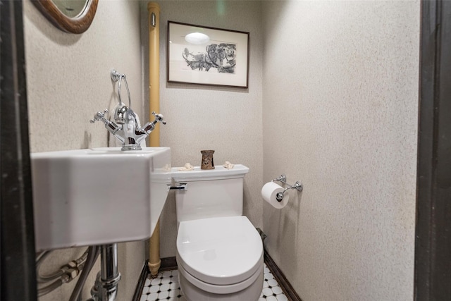 half bath featuring toilet and a textured wall