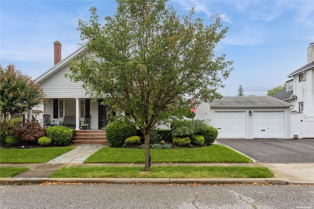 view of front of home with a garage, covered porch, and a front lawn