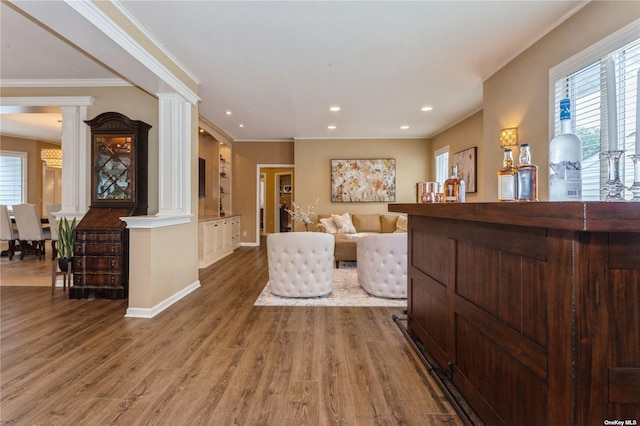 living area with a wealth of natural light, recessed lighting, ornate columns, and wood finished floors