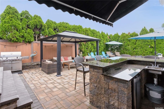 view of patio featuring an outdoor living space, fence, a gazebo, area for grilling, and a sink