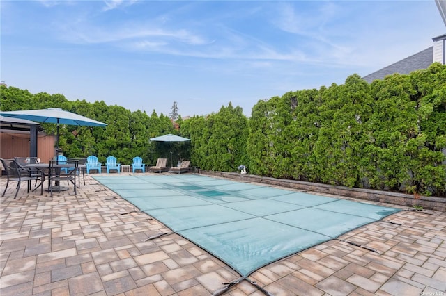 view of pool with a covered pool, outdoor dining area, and a patio