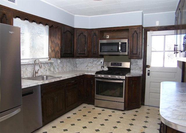 kitchen featuring dark brown cabinets, light floors, light countertops, stainless steel appliances, and a sink