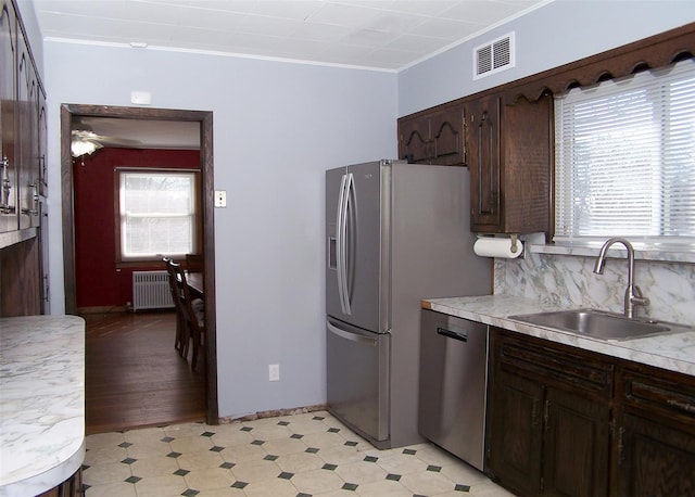 kitchen featuring light floors, radiator heating unit, a wealth of natural light, stainless steel appliances, and a sink