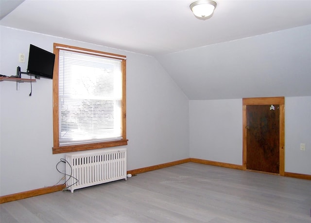 bonus room featuring baseboards, lofted ceiling, wood finished floors, and radiator heating unit