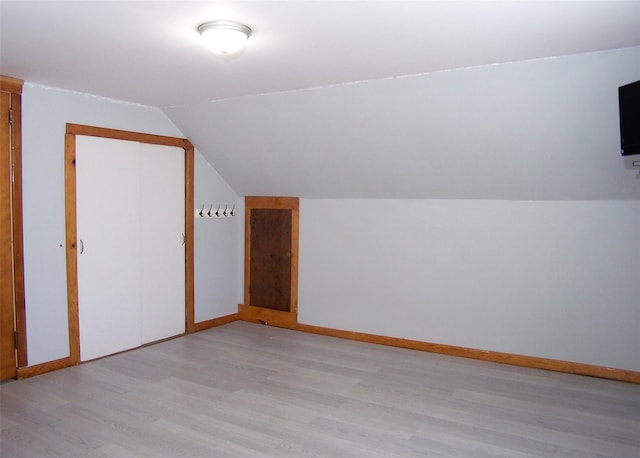 additional living space featuring light wood-style flooring, lofted ceiling, and baseboards