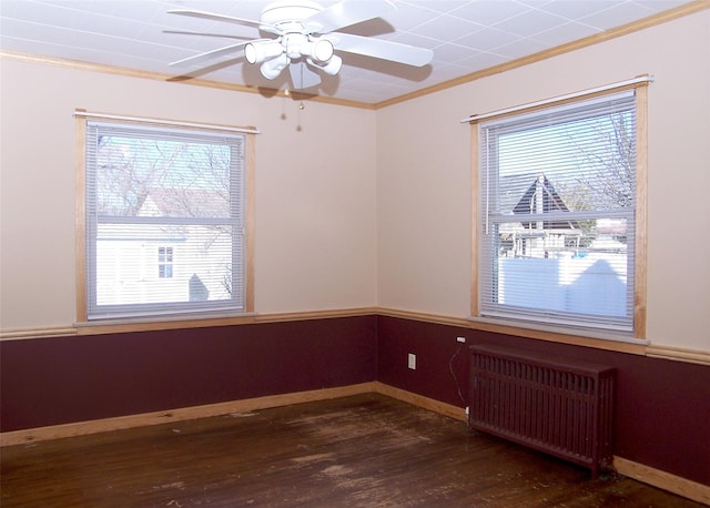 spare room featuring wood finished floors, radiator heating unit, baseboards, and ornamental molding