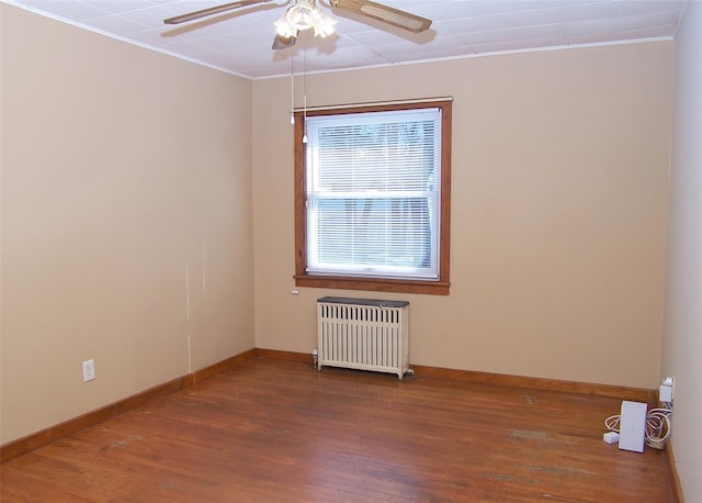 unfurnished room with a ceiling fan, wood finished floors, baseboards, radiator heating unit, and crown molding