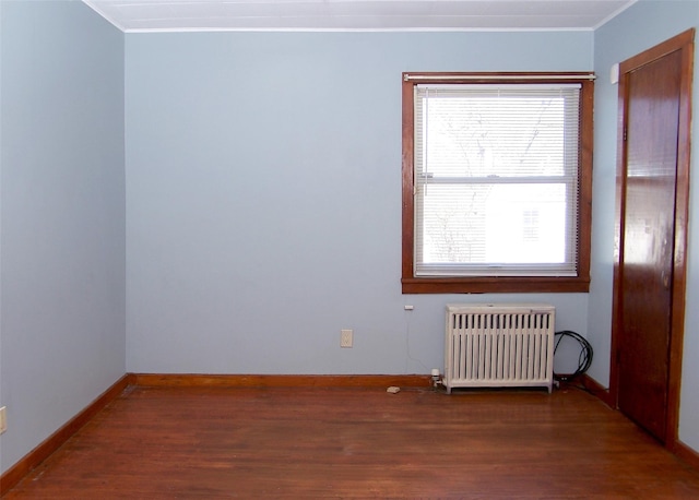 unfurnished room with crown molding, radiator heating unit, baseboards, and wood finished floors