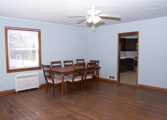 dining room featuring visible vents, baseboards, radiator, and wood finished floors