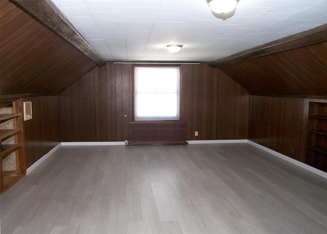 additional living space featuring lofted ceiling with beams, radiator heating unit, and wood finished floors