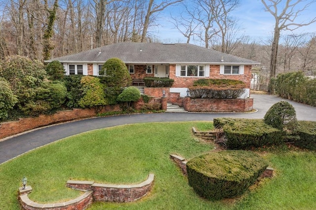 single story home with aphalt driveway, brick siding, and a front yard