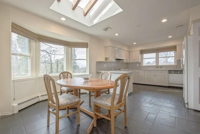 dining space with stone tile floors, visible vents, a skylight, recessed lighting, and a baseboard heating unit