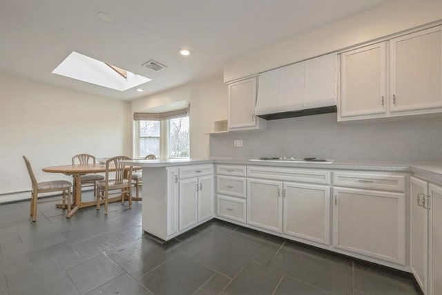 kitchen featuring visible vents, recessed lighting, a peninsula, light countertops, and white cooktop