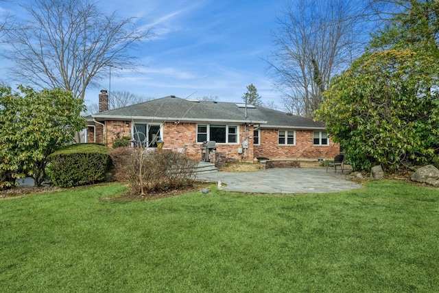 rear view of property featuring a patio, a yard, brick siding, and a chimney