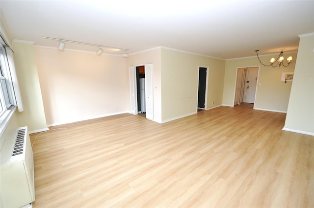 spare room with ornamental molding, light wood-style floors, baseboards, and a chandelier