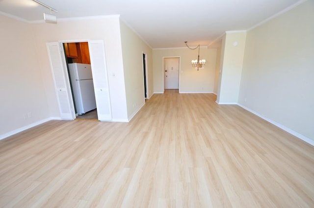 empty room featuring a notable chandelier, light wood-style flooring, baseboards, and ornamental molding