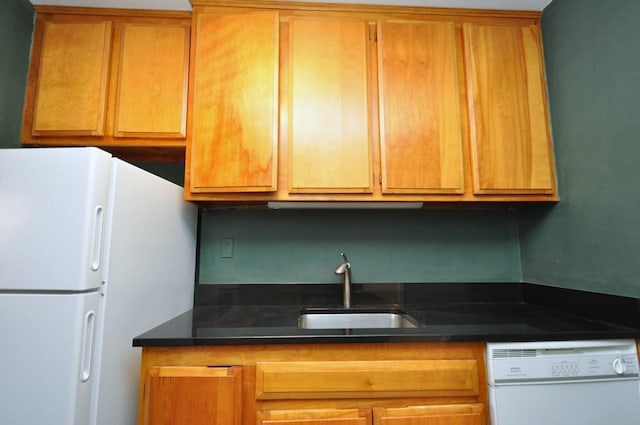 kitchen featuring white appliances, brown cabinets, and a sink