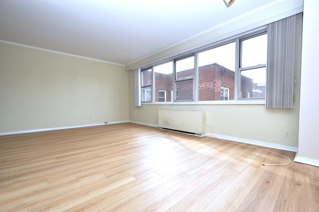 empty room featuring baseboards, wood finished floors, and ornamental molding