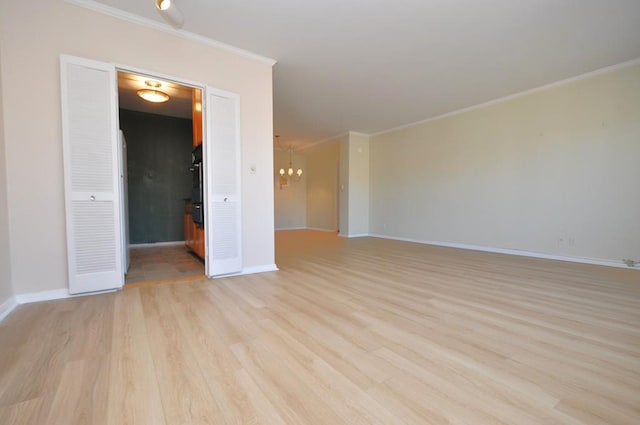 unfurnished room featuring a chandelier, baseboards, light wood-style floors, and ornamental molding