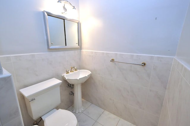 bathroom with toilet, tile walls, wainscoting, and tile patterned flooring