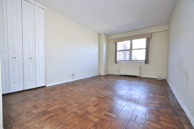 unfurnished bedroom with radiator and baseboards