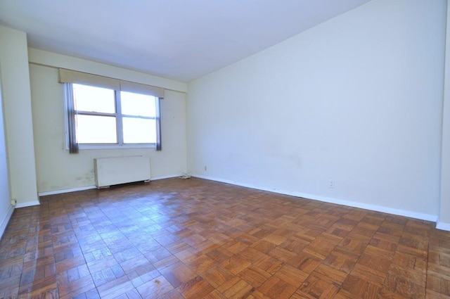 unfurnished room featuring radiator heating unit and baseboards