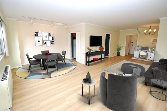 living room with track lighting, wood finished floors, an inviting chandelier, and ornamental molding