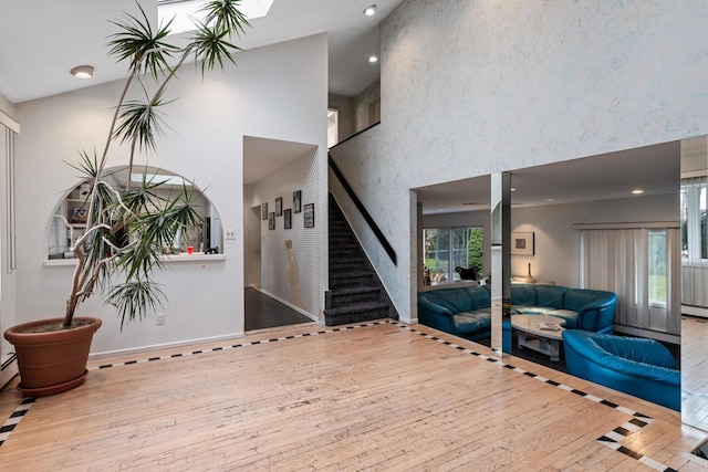 foyer entrance featuring baseboards, stairway, recessed lighting, a towering ceiling, and hardwood / wood-style flooring